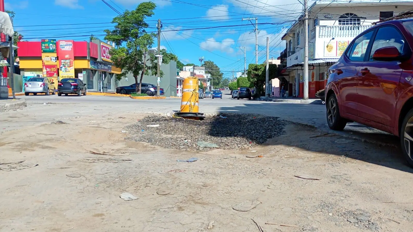 Excavación rellenada con grava y señalada con un tambo de seguridad en un cruce de calles